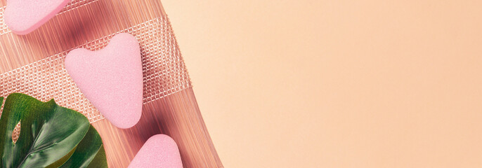Pink face sponges with monstera leaf. Cosmetic accessories. Banner