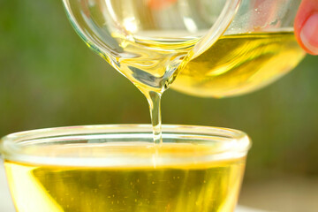 Pouring olive oil in the a glass bowl at stone kitchen and inside green garden view. Prepare for cooking concept. Healthcare and Beauty Concept.