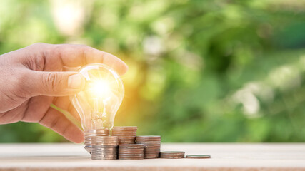 Man holding light bulb and many growth stack coins. concept saving money for finance accounting and idea for growing saving money.