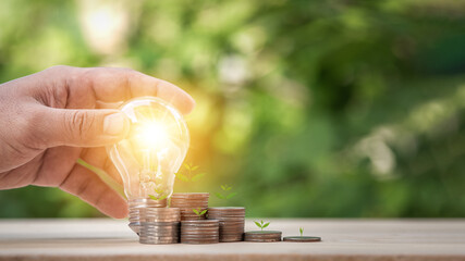 Man holding light bulb and many growth stack coins with plant in front. concept saving money for finance accounting and idea for growing saving money.