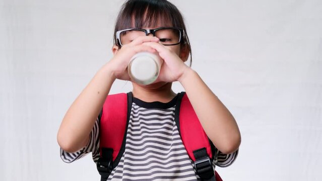 Cute schoolgirl drinking milk from a glass before going to school. Healthy nutrition for children. back to school concept