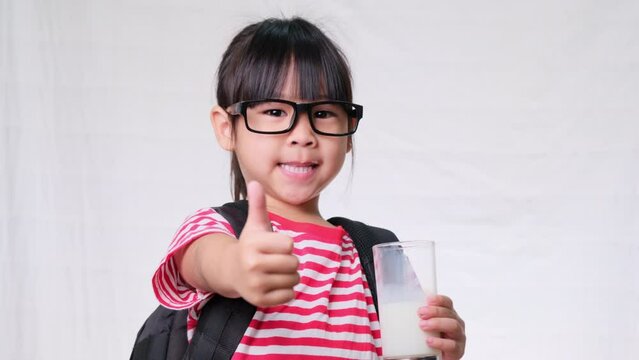 Cute schoolgirl drinking milk from a glass before going to school. Healthy nutrition for children. back to school concept