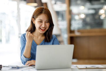 Excited happy woman looking at the laptop computer screen, celebrating an online win, overjoyed young asian female screaming with joy, isolated over a white blur background