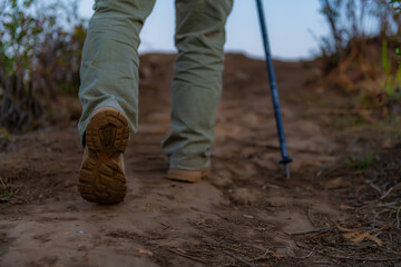 Feet of male climber walking on a hiking trail . Active man traveling on nature.