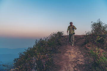 Young man with a backpack enjoying the sunset on the top of the mountain Travel traveler on valley scenery mockup background Mountain climbers watch the sunlight shining on their country journey.