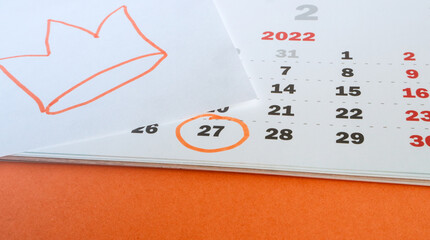 Close-up of a paper calendar on April 27, 2022 with an orange background and a hand-drawn crown in the traditional colors of the King's Day celebration in the Netherlands