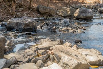 River flowing through large boulders in mountain wilderness park.