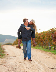 Having fun while messing around. A young man carrying his girlfriend on his back while taking a...