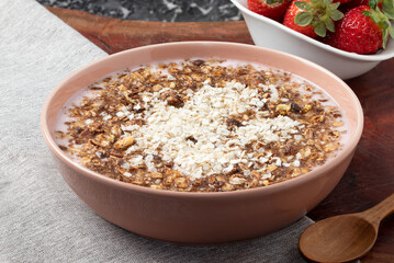 A bowl of strawberry yogurt mixed with granola and quinoa.