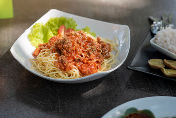 Spaghetti in a beautiful white plate placed on the table.