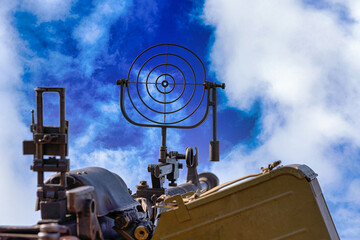 fragment of an anti aircraft machine gun, a round sight is aimed at clouds sky - 491148962