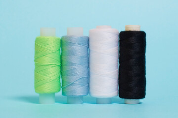 Coils with black, white, blue and green threads on a blue background