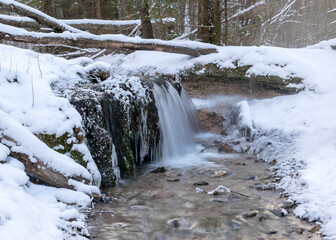 Obraz premium landscape with a small rapid river flowing over frozen rocks through a wild ravine