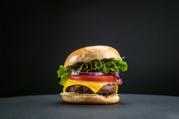 Tasty homemade beef burger with fresh ingredients on dark background, close-up view..