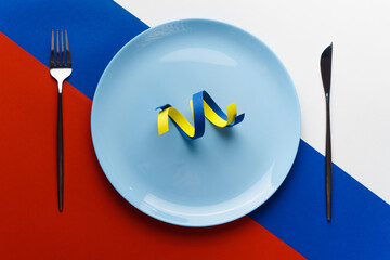 Blue and yellow ribbons as symbol of Ukraine on plate on flag of Russia. Russia want to eat Ukraine