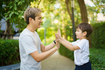 Fototapeta premium Happy Asian little boy enjoy playing and walking at the park with daddy.