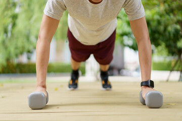 Active Asian sportsman making a body weight exercise, man doing push up workout with dumbbell. 