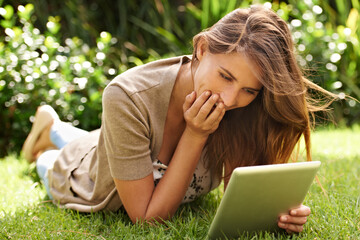 Happiness where technology and nature meet. Shot of a woman enjoying using her digital tablet in the outdoors.