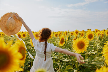 woman holding a straw hat over her head nature sunflowers countryside
