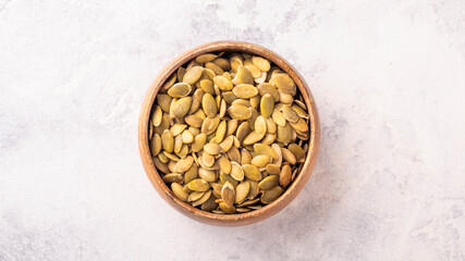Raw organic pumpkin seeds in a bowl. Top view