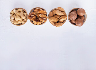 Nuts various in a different bowl on white background. Top view. Space for text