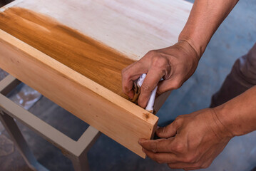 Applying varnish to a cabinet drawer with a piece of cloth. First coating. At a furniture and woodworking shop.