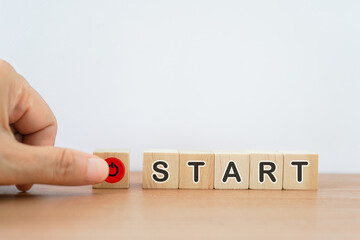 word start on wooden cubes with blurred senior's hand pressing the start button for make a new...