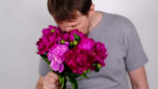 Man inhales fragrance of purple peonies and gives bouquet. Selective focus. Slow motion