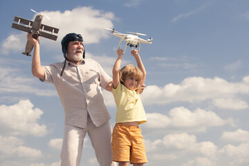 Grandfather and grandson hold plane and drone quadcopter. Child boy pilot aviator with plane dreams of flying.