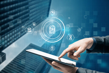 Close up of businessman hand pointing at tablet with abstract glowing id fingerprint web protection and security interface on blurry blue bokeh city background. Identification