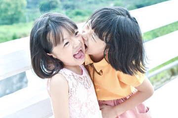 Two yellow-skinned Asian girls are having fun in the park with smiling faces.