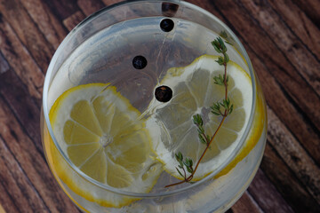 Close-up of a delicious gin and tonic with lemon slices and juniper seeds.