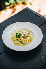 Carbonara in white plate on black wooden table
