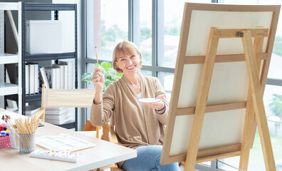 Art school. Creativity and people concept. Happy senior woman artist with easel and pencil drawing picture at studio
