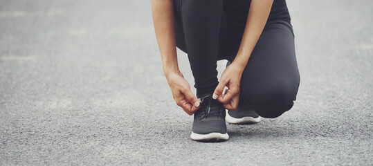 Running shoes runner woman tying laces for autumn run in forest park. Runner trying running shoes getting ready for run. Jogging girl exercise motivation heatlh and fitness.
