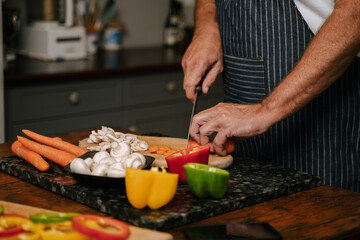 Caucasian senior male chopping vegetables in kitchen