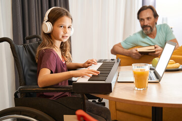 Disabled teenager learning to play the synthesizer with his father