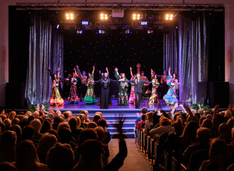 A collective of musicians, singers and dancers in gypsy costumes perform on stage.