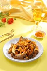 Crispy fish crackling decorated in yellow table with ingredient and flower for food advertising 
