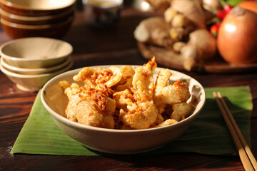 Crispy pork crackling decorated in wooden table with sauce ingredient and oil lamp for food advertising 