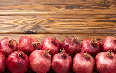 Ripe pomegranates stacked on a wooden background with a place to copy. Selective focus.