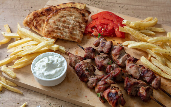 Souvlaki dish, Greek meat food. Grilled skewers and pita bread on wooden table, overhead
