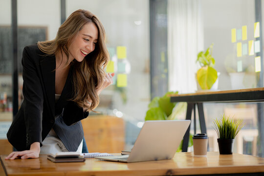 Woman gesturing and looking at the laptop, businesswoman checking company monthly sales and pretending to be happy as sales meet planned targets according to policy. Sales management concept.
