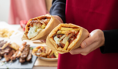 Gyro pita Shawarma, sliced meat tzatziki and vegetable wrap in male hand, close up view.