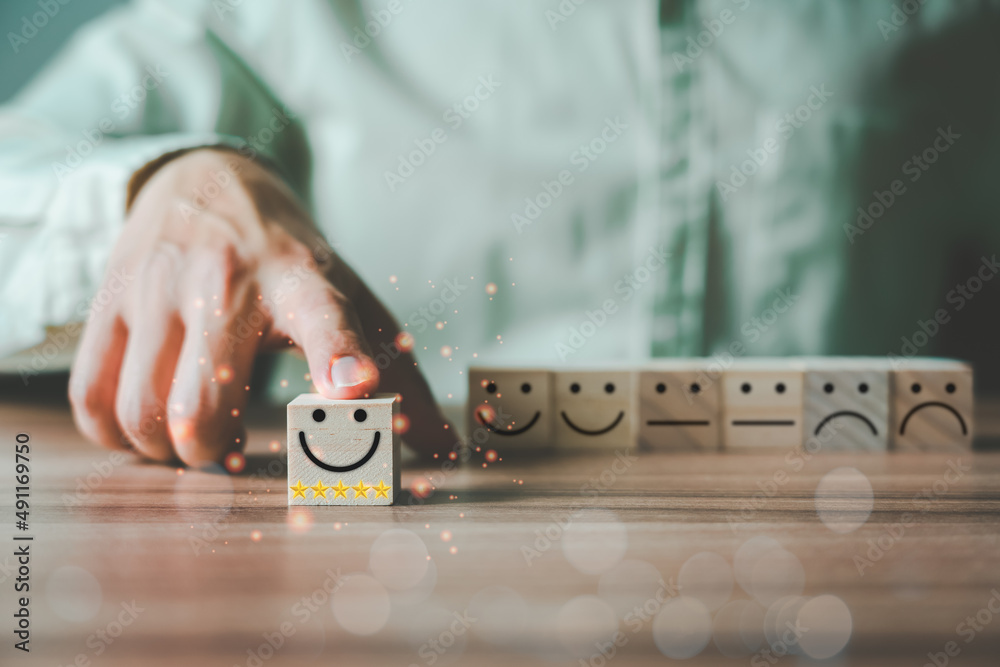 Poster businessman's hand moves a smile face icon with 5 star satisfaction on a wooden cube block forward. 
