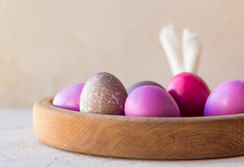 PREPARATIONS FOR EASTER. A WOODEN TRAY WITH PAINTED EGGS AND A PAPER RABBIT. copy space