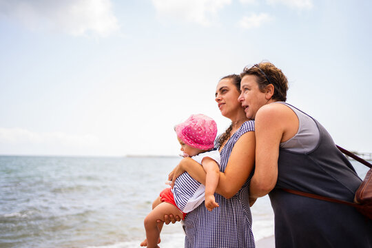 Family of three generation of women embracing next to the beach