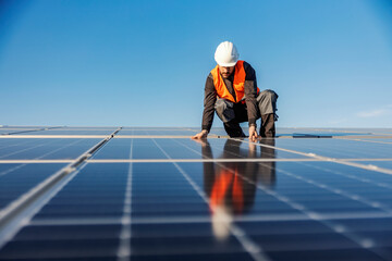 A handyman installing solar panels on the rooftop. - obrazy, fototapety, plakaty