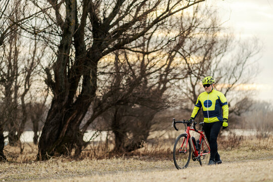 A senior bicyclist pushing bicycle and walking in nature.