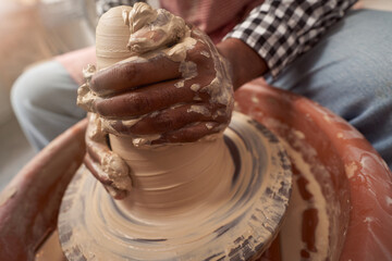 Skilled ceramist creating piece of pottery in his workshop